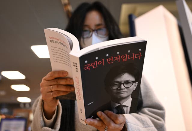 <p>A woman reads Han Dong Hoon’s memoir ‘The People First’ at a bookstore in Seoul</p>